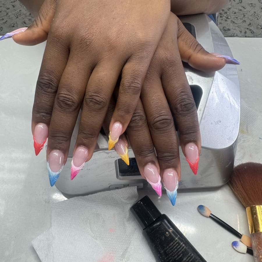 Stiletto nails with colorful French tips in red, yellow, blue and pink